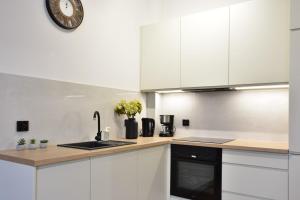 a kitchen with white cabinets and a clock on the wall at VacationClub - Old Town Apartament 1 in Kłodzko