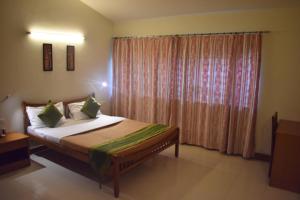 a bedroom with a bed and a window with curtains at Ornate Villa in Pune