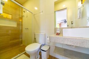 a bathroom with a toilet and a shower and a sink at Pousada Tropicarim in Itacimirim