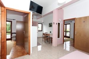 a kitchen and dining room with a table and a television at Apartments Spavalo in Pag