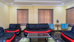 a waiting room with couches and tables and windows at Obec’s Apartment in Accra