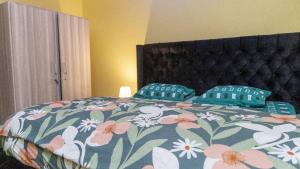 a bed with a floral comforter and two pillows at Obec’s Apartment in Accra