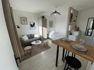 een woonkamer met een bank en een tafel met stoelen bij Studio cosy à 200m de la plage in Ouistreham
