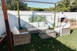 a patio with a white couch and chairs in a yard at Villa Parra in Chiclana de la Frontera