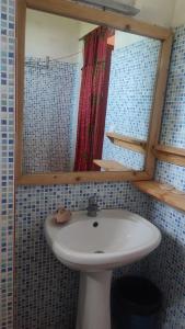 a bathroom with a white sink and a mirror at AKINE TI KASSO piscine in Diembéreng