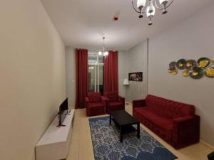 a living room with a red couch and two red chairs at Wonderful 1bhk at silicon oasis in Dubai