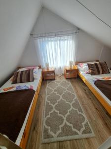 two beds in a room with a window at Domek pod Świerkami in Czarna