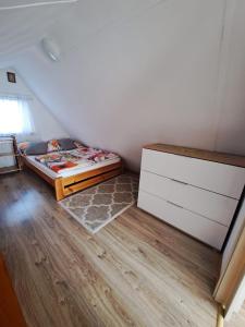 niewielka sypialnia z łóżkiem i komodą w obiekcie Domek pod Świerkami w mieście Czarna