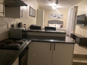 a kitchen with a counter top and a room with a bed at Edenvale corner in Edenvale