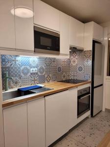 a kitchen with white cabinets and a microwave at L'univers au blanc. in Strasbourg +22 photos
