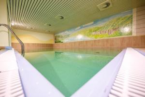a swimming pool in a house with a painting on the wall at Hotel Sportwelt Radeberg in Radeberg