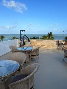 un patio con tavoli, sedie e vista sull'oceano di Flat Beira Mar de Tambaú apto 206 a João Pessoa