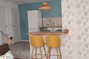 uma cozinha com dois bancos de bar amarelos num balcão em Tu casa em Almeria