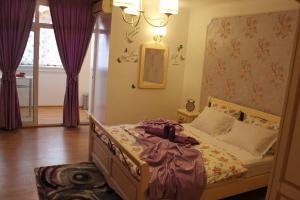 - une chambre avec un lit dans un dortoir doté de rideaux violets dans l'établissement Boutique Apartments, à Galaţi
