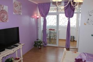 - un salon avec des rideaux violets et une télévision dans l'établissement Boutique Apartments, à Galaţi