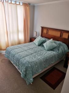 a bedroom with a bed with a green comforter at Condominio Costamar in Coquimbo