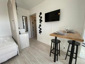 een kamer met een tafel en een televisie en een bed bij Studio cosy à 200m de la plage in Ouistreham