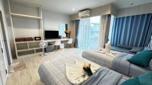 a bedroom with two beds and a desk with a television at AURIFLEX HOUSE in Krabi town
