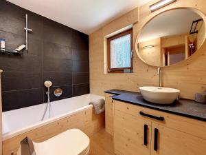 ein Badezimmer mit einem Waschbecken, einer Badewanne und einem Spiegel in der Unterkunft La Ruinette - Cosy 2 Bed With Stunning Views in Verbier