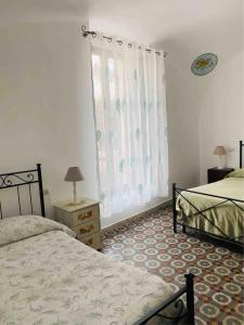a bedroom with two beds and a window with curtains at Casa Cardi in Sperlonga