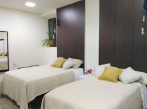 Cette chambre comprend 2 lits avec des draps blancs et des oreillers jaunes. dans l'établissement Ajayu Sucre, à Sucre
