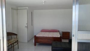 a small bedroom with a bed and a chair at Apto Temporada Cabo Frio in Cabo Frio