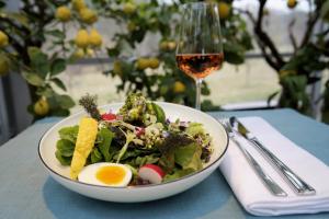 eine Schüssel Salat mit einem Ei und einem Glas Wein in der Unterkunft Flora auf Gut Guntrams in Schwarzau am Steinfelde
