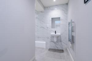 a white bathroom with a sink and a bath tub at Designer Central Leeds Home by PureStay sleeps 5 in Leeds