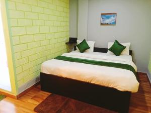 a bedroom with a large bed with green pillows at Manikarn Resort in Joshīmath