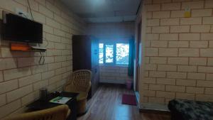 een woonkamer met een tv aan een bakstenen muur bij Manikarn Resort in Joshimath