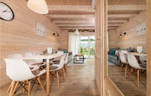 a dining room with white chairs and a clock at Beautiful Home In Ustronie Morskie With Kitchen in Ustronie Morskie