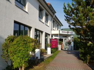 a white building with a tree in front of it at Hotel Sportwelt Radeberg in Radeberg