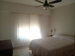 a bedroom with a bed with a ceiling fan and a window at LOS CACTUS in Tandil