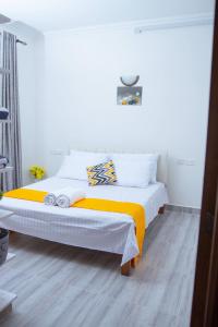 1 dormitorio con 1 cama con sábanas blancas y amarillas en Kezmo Siloam Paradise en Mombasa