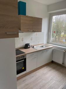 a kitchen with white cabinets and a sink and a window at Monteurswohnungen Ferropolis in Gräfenhainichen
