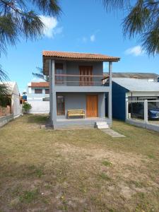 uma casa com um banco em frente a um quintal em Casa de Praia - Frente para o MAR em Xangri-lá