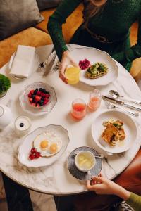 zwei Personen sitzen an einem Tisch mit Teller Essen in der Unterkunft Rosewood Munich in München