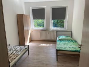1 dormitorio con 2 camas y 2 ventanas en Monteurswohnungen Ferropolis, en Gräfenhainichen