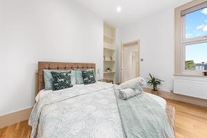 a white bedroom with a large bed and a window at Modern Spacious 1 Bed Flat near Richmond Park in London
