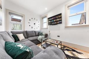 a living room with a couch and a clock on the wall at Modern Spacious 1 Bed Flat near Richmond Park in London