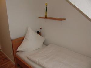 Cama pequeña con almohada blanca y estante en Venner Gasthaus, en Ostercappeln