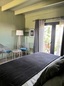 ein Schlafzimmer mit Bett, Stühlen und einem Fenster in der Unterkunft La Guarda Bed and Breakfast in Zapallar