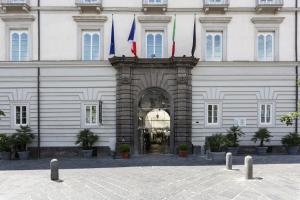 ein weißes Gebäude mit Flaggen davor in der Unterkunft Palazzo Caracciolo Naples in Neapel