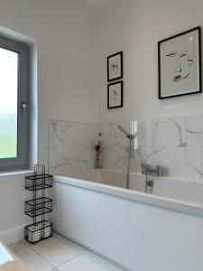 baño blanco con bañera y ventana en Sea Vista - Rathmullan en Rathmullan