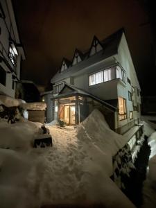 uma casa está coberta de neve à noite em Sakurasou Lodge em Nozawa Onsen