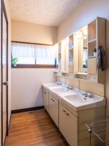 een badkamer met 2 wastafels en een spiegel bij Sakurasou Lodge in Nozawa Onsen