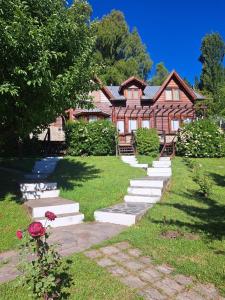 a house with stairs in front of a yard at Cabañas La Terraza in El Bolsón
