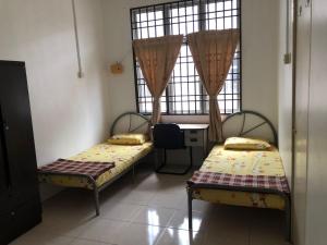 Habitación con 2 camas, mesa y ventana en Padusi Homestay en Kampar