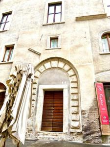 - un bâtiment avec une porte en bois et une arche dans l'établissement Vacanze Romane al Portico d'Ottavia, à Rome
