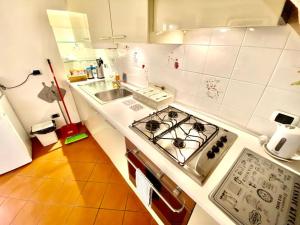 - une cuisine blanche avec cuisinière et évier dans l'établissement Vacanze Romane al Portico d'Ottavia, à Rome
